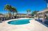 Inviting outdoor pool area with elegant lounge chairs, surrounded by lush palm trees under a bright blue sky.