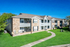 Charming two-story apartment complex with brick facade and lush green lawn, featuring spacious balconies for relaxation.