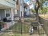 Inviting apartment patio with cozy seating area, modern grill, and charming fenced garden space amidst lush greenery.