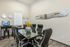 Modern office space with sleek black chairs around a glass table, featuring contemporary wall art and vibrant flowers.