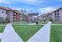 Charming apartment complex featuring modern buildings with stylish balconies, surrounded by lush green lawns and a cozy outdoor seating area.