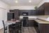 Modern kitchen with sleek dark cabinets, stainless steel appliances, and a stylish wooden dining set, offering an inviting atmosphere for meals.