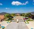 Charming gated apartment community with lush landscaping, ample parking, and inviting brick architecture under a bright blue sky.