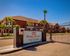 Inviting entrance of Mission Terrace Apartments with secure gated access, surrounded by lush palm trees and vibrant brick buildings.