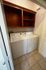 Convenient in-unit laundry room featuring a modern washer and dryer set, complemented by sleek wooden shelving.