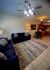 Inviting open-plan apartment showcasing a cozy living room with plush navy sofas, elegant lighting, patterned rug, and a modern kitchen with wooden cabinetry.
