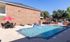 Inviting outdoor pool area featuring comfortable lounging chairs, red umbrellas, and a charming brick building, perfect for relaxation.