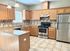 Modern kitchen featuring oak cabinetry, sleek stainless steel appliances, and elegant tile flooring.