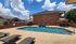 Inviting apartment complex poolside with comfortable loungers, umbrella-shaded seating, and a serene sky backdrop.