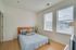 Bright, cozy bedroom with a modern design featuring a comfortable bed, large windows, and natural lighting.