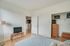 Inviting bedroom with natural light, featuring a modern TV setup, wooden furniture, and spacious closet.