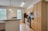 Spacious modern kitchen featuring light wood cabinetry, stainless steel appliances, and natural light from large windows.