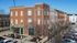 Picturesque urban apartment building with vibrant red brick facade and large windows, located in a lively neighborhood.