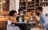 Four friends enjoying coffee together in a cozy caf&eacute; setting.