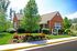 Brick clubhouse surrounded by well-maintained landscaping and lush greenery on a sunny day.