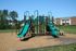 Inviting playground with green slides and climbing structures set in a sunny residential area.