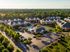 Aerial view of a picturesque apartment complex with lush greenery and a central swimming pool.