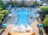 Aerial view of a vibrant pool area with sun loungers and umbrellas in an upscale apartment complex.