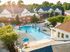 Vibrant aerial view of a sunlit pool surrounded by lush greenery and elegant apartment buildings.