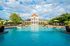 Inviting swimming pool in front of a stylish clubhouse, surrounded by lush greenery and sun loungers.