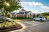 Sunny day view of a community building with classic brick architecture, surrounded by lush greenery.