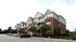 Elegant multi-story brick and siding apartment complex with balconies and lush landscaping.