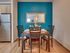 Inviting dining area with a wooden table, four chairs, and a blue accent wall.