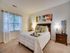 Inviting bedroom with a plush bed adorned with vibrant accent pillows, soft lighting, and artistic decor.