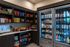 Stylish snack and beverage area featuring open shelves of chips and an illuminated fridge with an assortment of drinks and ready-to-eat meals.