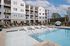 Elegant apartment complex with poolside lounge chairs and modern design.