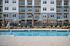Chic apartment building facade with a pristine pool and comfortable sun loungers.