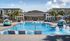 Inviting luxury apartment pool area with modern sun loungers and vibrant palms.