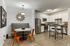 Stylish kitchen with white cabinets, stainless steel appliances, and a cozy dining nook with orange chairs.