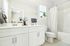 Bright and modern bathroom featuring a double sink vanity, stylish decor, and a bathtub with a patterned shower curtain.
