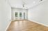 Airy living room with natural wood flooring, a ceiling fan, and large glass doors leading to a patio.