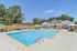 Inviting swimming pool surrounded by sun loungers and modern clubhouse with sunny skies.