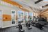 Modern gym with exercise bikes and treadmills, featuring motivational wall art and bright windows.