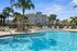 Inviting outdoor pool area surrounded by palm trees and modern apartment buildings under a clear blue sky.