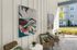Stylish outdoor lounge with modern wicker chairs, vibrant abstract art, and lush greenery.