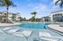 Resort-style pool area with palm trees and modern apartment buildings in the background.