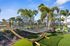 Bright outdoor area featuring a hammock surrounded by lush palm trees and modern apartment buildings.