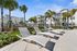 Luxurious apartment complex with palm trees, sun loungers, and modern architecture.