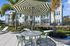 Chic outdoor seating area at a modern apartment complex with stylish green-striped umbrella and surrounding palm trees.
