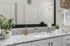 Stylish bathroom vanity with a granite countertop, greenery, and a large mirror.