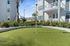 Charming apartment putting green with lush greenery and a modern building backdrop.