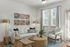 Contemporary living room with stylish decor, featuring a cozy white sofa, abstract wall art, and elegant gold floor lamps.