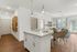 Bright and modern open-concept living area featuring a stylish kitchen island, dining set, and cozy living room with natural light.