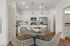 Modern kitchen with sleek white cabinets, stainless steel appliances, and cozy dining setup with woven chairs.