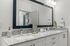 Sleek bathroom vanity with granite countertop and large mirror, featuring modern lighting.