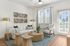 Bright and stylish living room with white sofa, art pieces, and wooden accents under natural light.